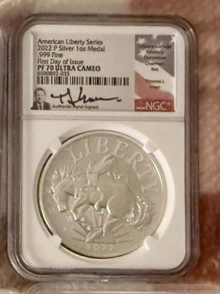 The Demo’s 2022-P American Liberty silver medal in its NGC PF 70 Ultra Cameo holder, with First Day of Issue label and Thomas J. Uram signature